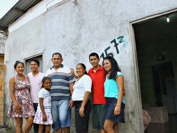 Família de Valmir na frente da casa construída com dinheiro adquirido enquanto trabalhava no hotel (Foto: Leandro Tapajós/G1 AM)